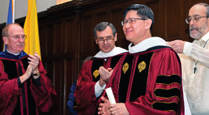 Professor Henry Schwalbenberg, right, helps Cardinal Tagle adjust his hood at the honorary degree ceremony. To the left are Father McShane and Edward Stroz, GSB ’79, vice chair of Fordham’s Board of Trustees. Photo by Bruce Gilbert