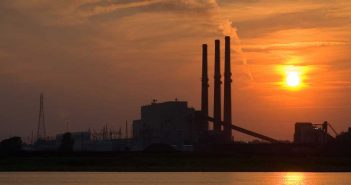 a coal power plant in an orange sky at sunset