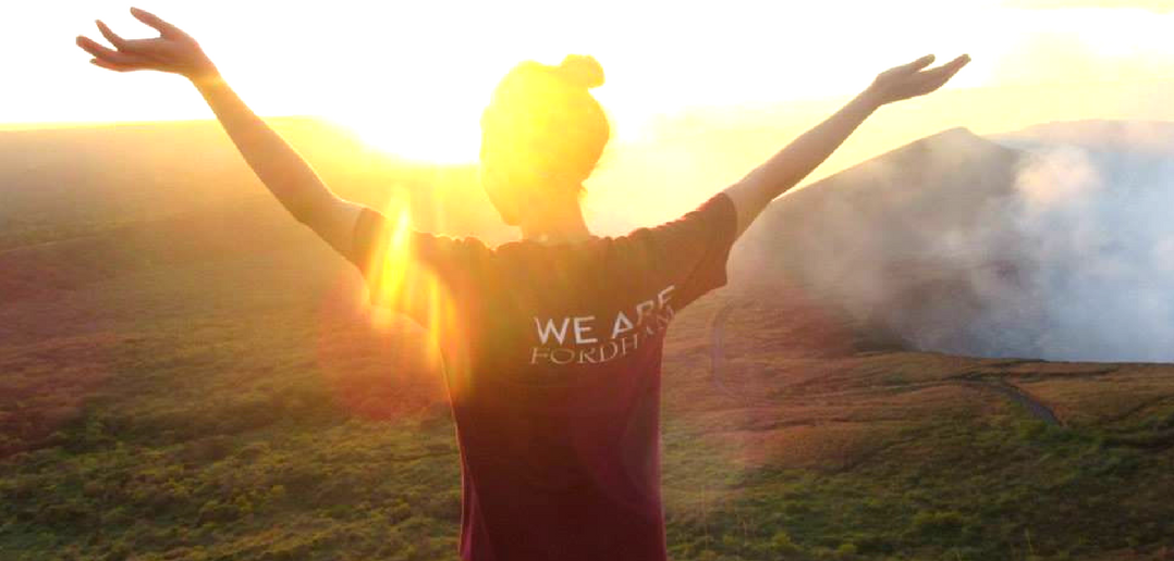 Woman in Fordham tshirt standing in a field in the early morning