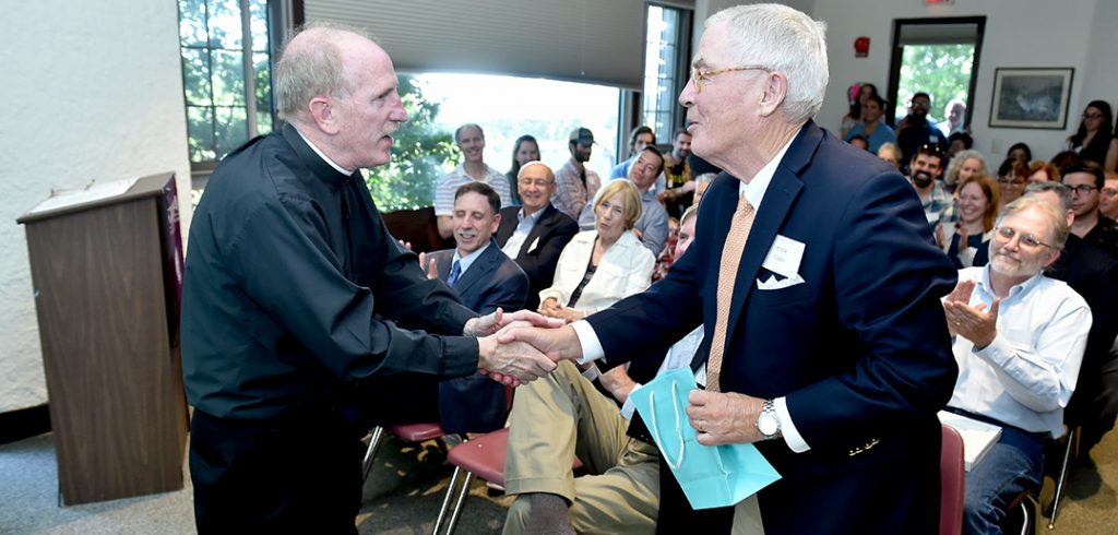 Joseph M. McShane shakes hands with Peter Calder at the 50th anniversary celebration of the Calder Center