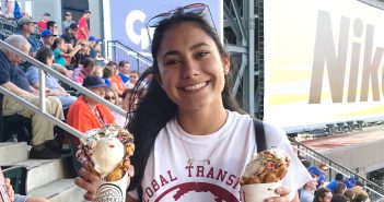 Female international student with black hair holding two ice cream cones at a Mets game