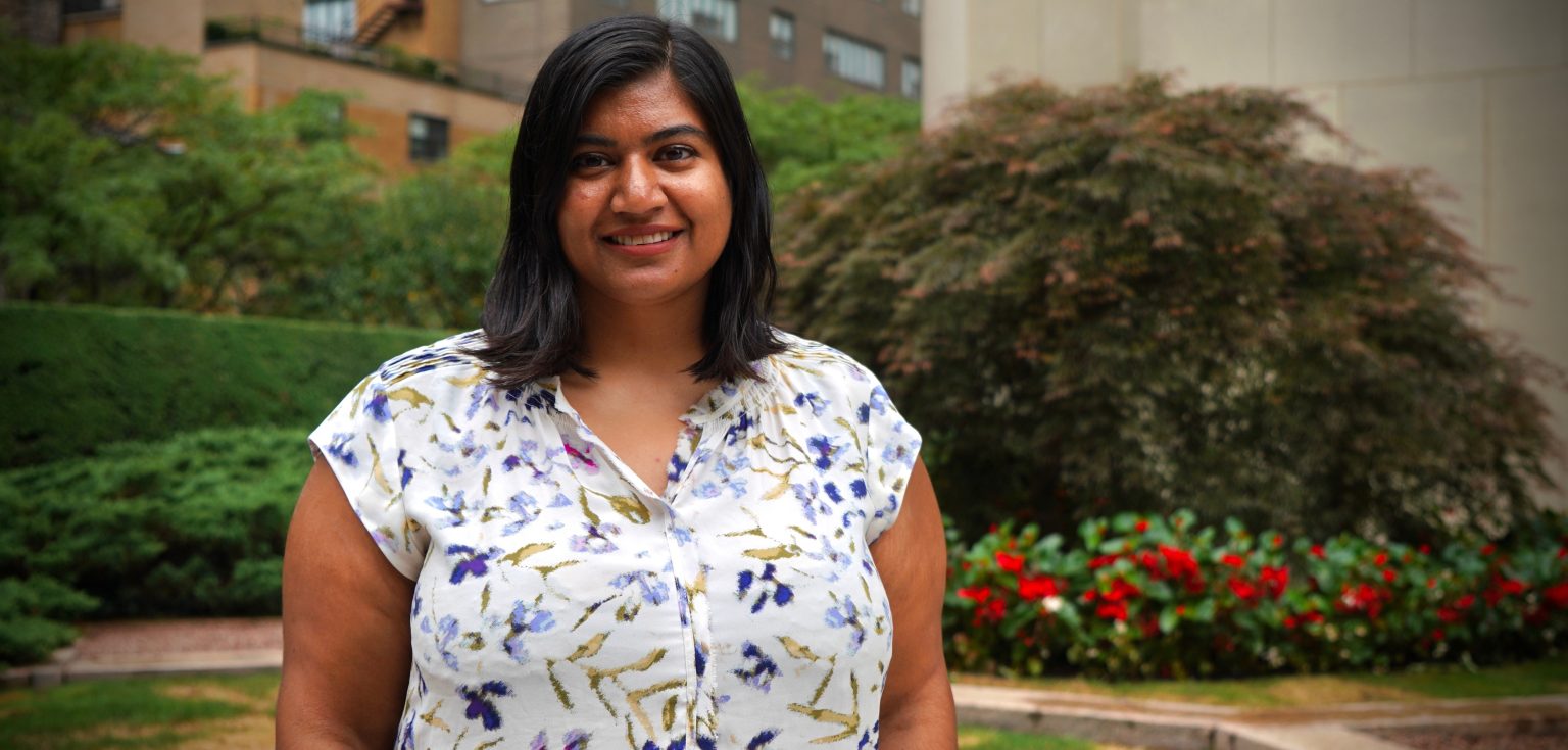 A woman wearing a floral shirt smiles.