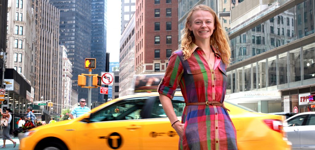 A woman poses in front of a taxi in NYC