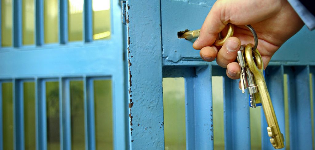 stock art of hand insterting key into jail cell