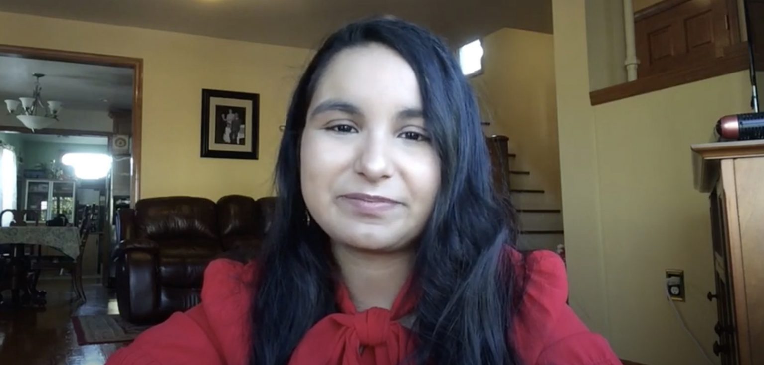 A woman wearing a red blouse smiles.