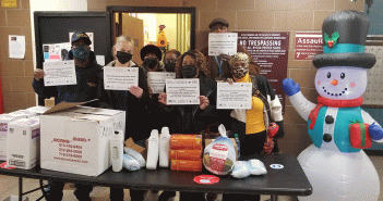 People from the Amsterdam Houses and Amsterdam Addition holding signs of gratitude for Fordham while stanidng in fron tof turkeys and other Thanksgiving supplies