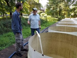 Michael Kausch and John Wehr speaking next to tanks of water 