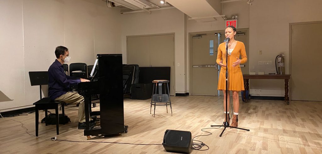 A man plays piano while a girl sings