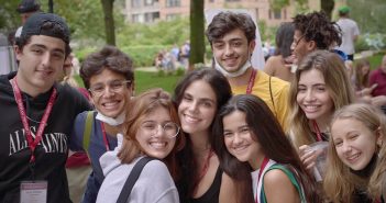 A group of first-year students huddle in a group and smile.