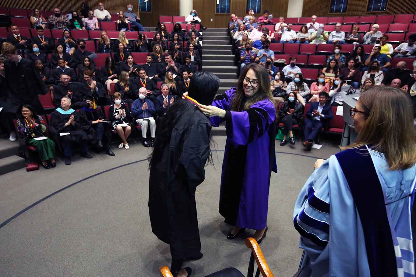 Donna Rapaccioli places a medalaround a students neck on stage