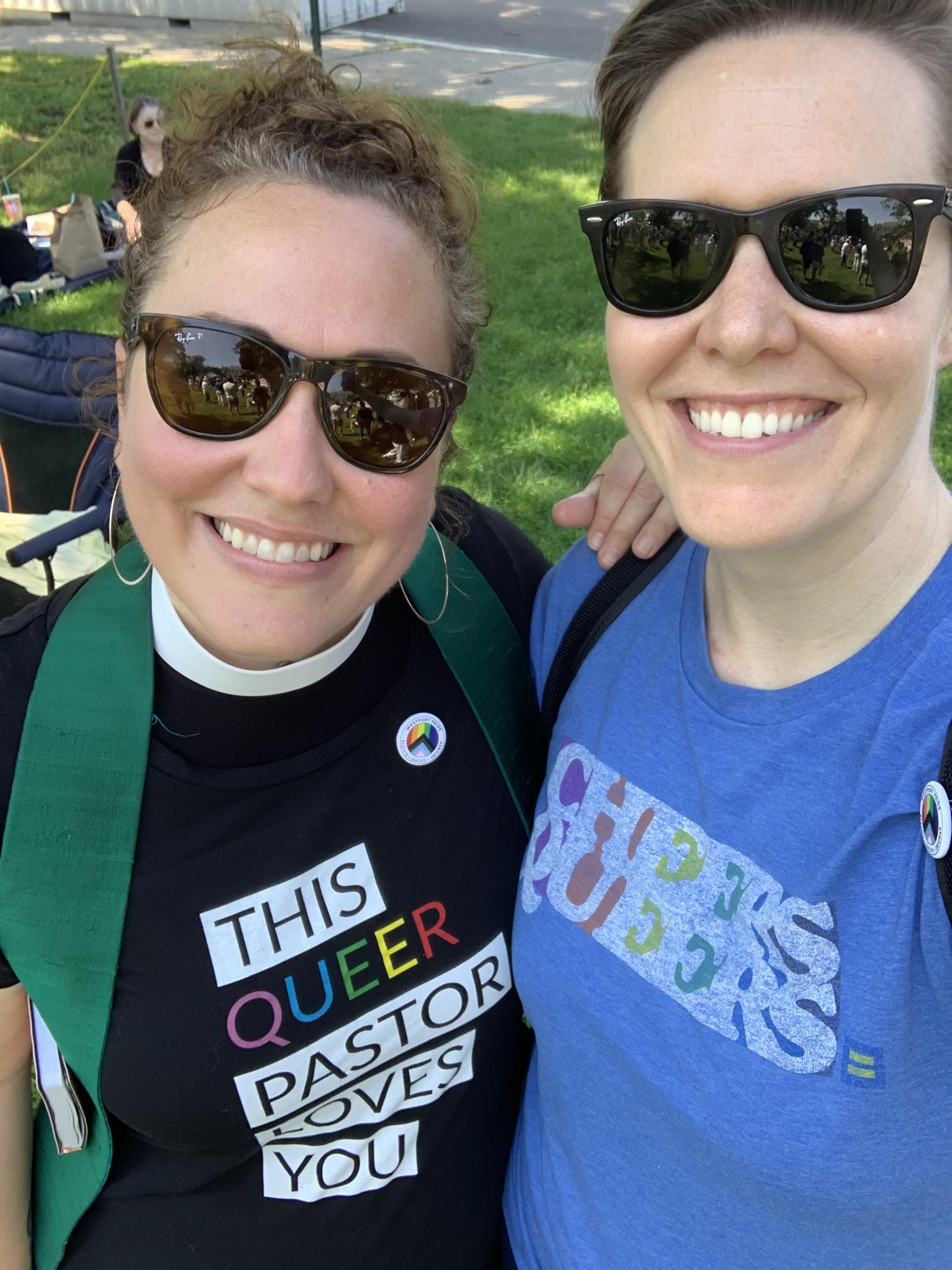 Two women wearing sunglasses smile.