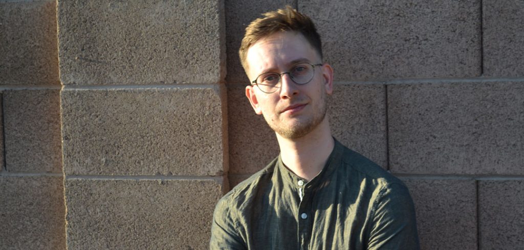 Andrew Hudson standing in front of a wall.