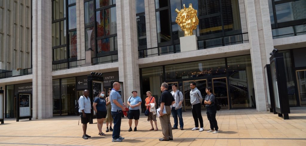 A group of people stand in a circle in front of a buildng.