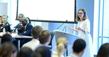 Law Alumni Share Timeless Advice with First-Year Law Students A woman speaks in front of a podium while seated people in the background look on.