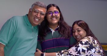 A girl is hugged by her two parents.