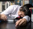 Student teen sleeping sit at table at library study online on laptop with textbook