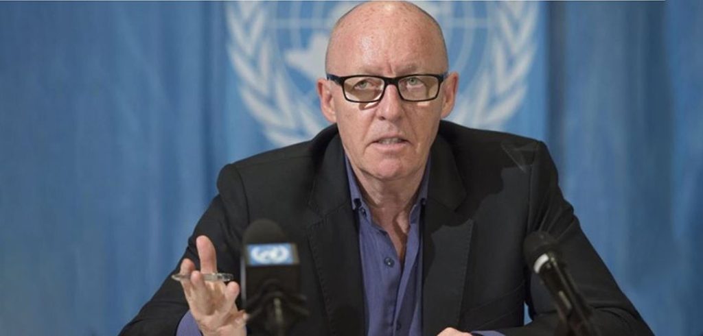 Jamie McGoldrick speaking in front of a United Nations logo