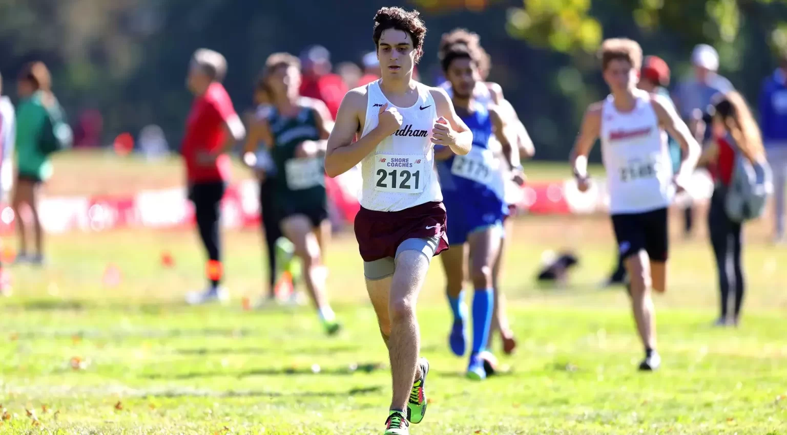Cross Country’s Matthew Febles Named A-10 Men’s Performer of the Week Matthew Febles running in cross country uniform, people behind him running as well.