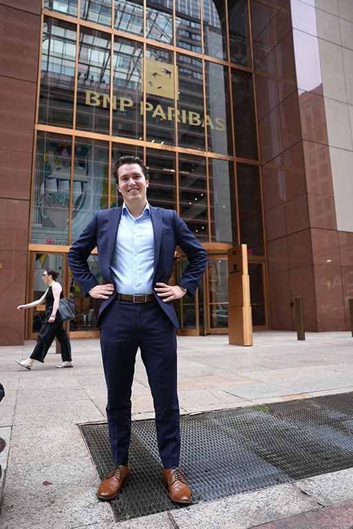 A man standing in front of a building on a sidewalk.