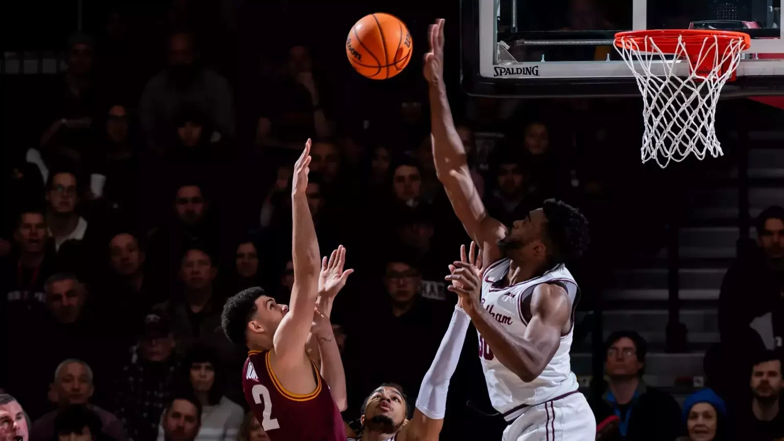 Tsimbila Named to Atlantic 10 Preseason All-Defensive Team Two men playing basketball on opposing teams, jumping in air to shoot and block a basket.