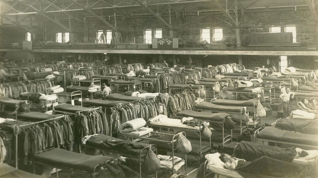 How Rose Hill Gym Sheltered Troops in World War II Black and white image shows dozens of cots arrayed on the Rose Hill Gym floor, with a small number of soldiers resting on them