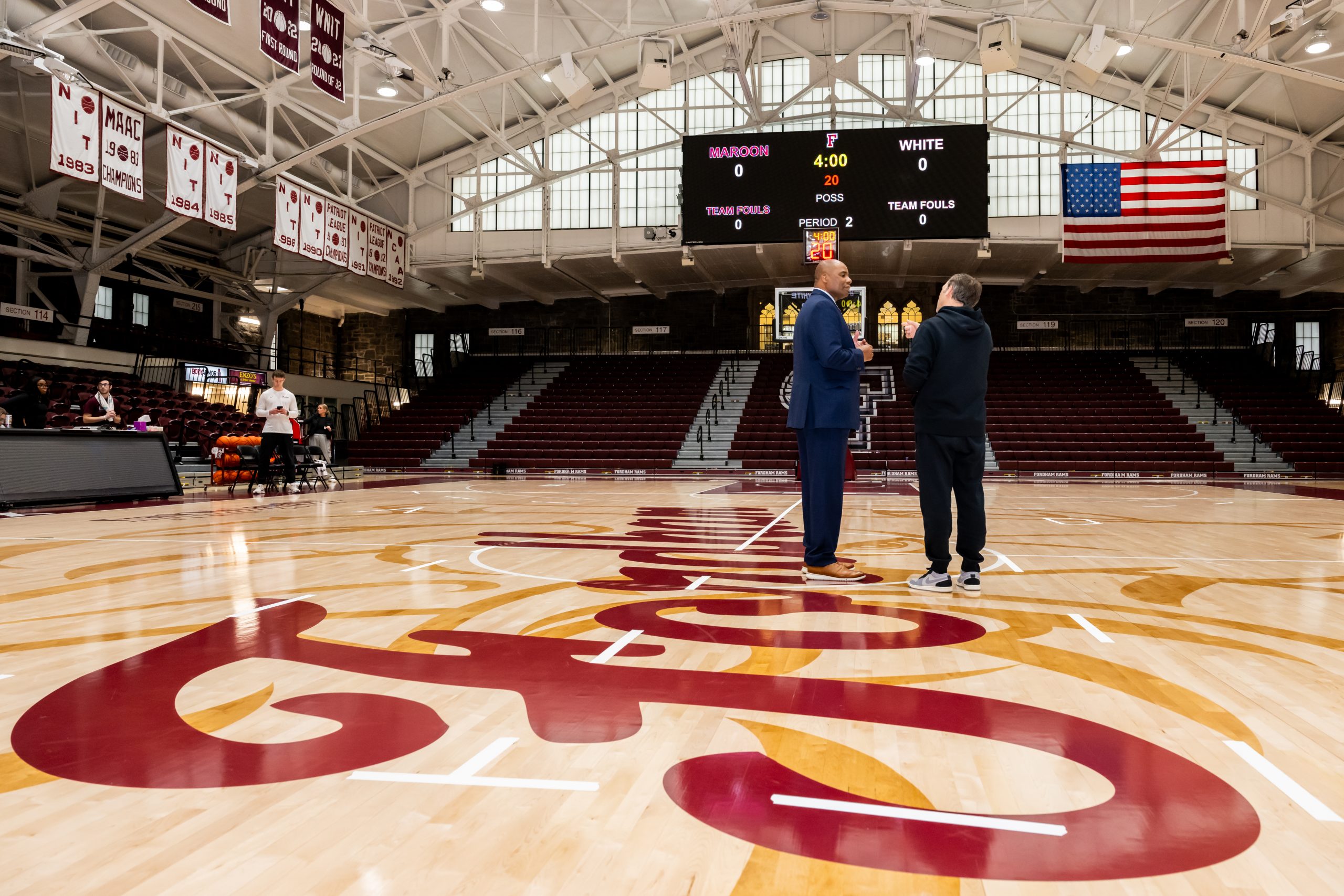 Charles Guthrie speaks with men’s basketball head coach Keith Urgo in the Rose Hill Gym. Photo courtesy of Fordham Athletics