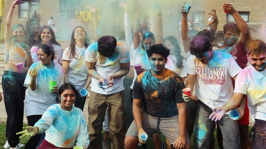 Group of students celebrating Holi, colored powders all over their clothes.