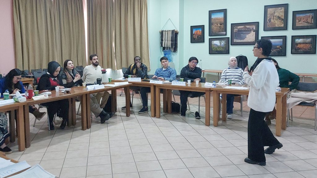 Training to Heal a Broken World A group of students seated at tables, listening to an instructor standing in front of them.