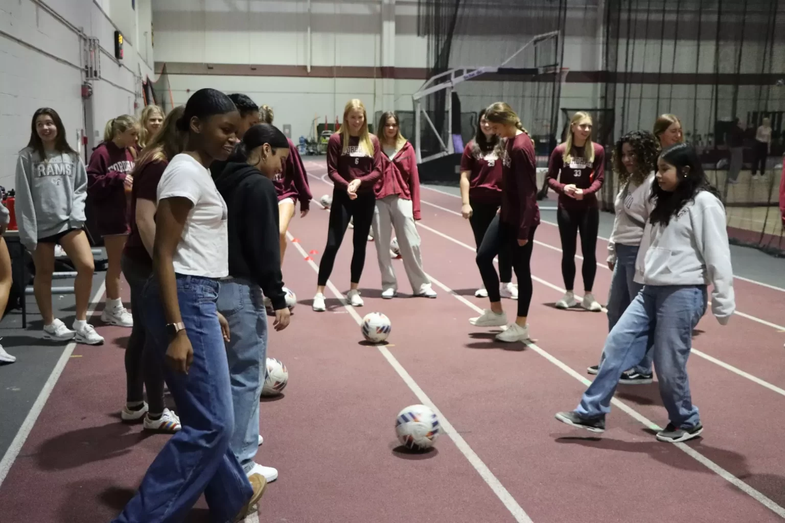 Fordham to Host Clinic for National Girls and Women in Sports Day Young women standing in group, soccer balls on ground.