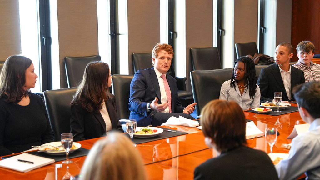 Joseph P. Kennedy III sits at a table, surrounded by students