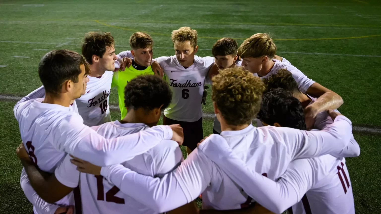 Group of mens soccer team in huddle on field