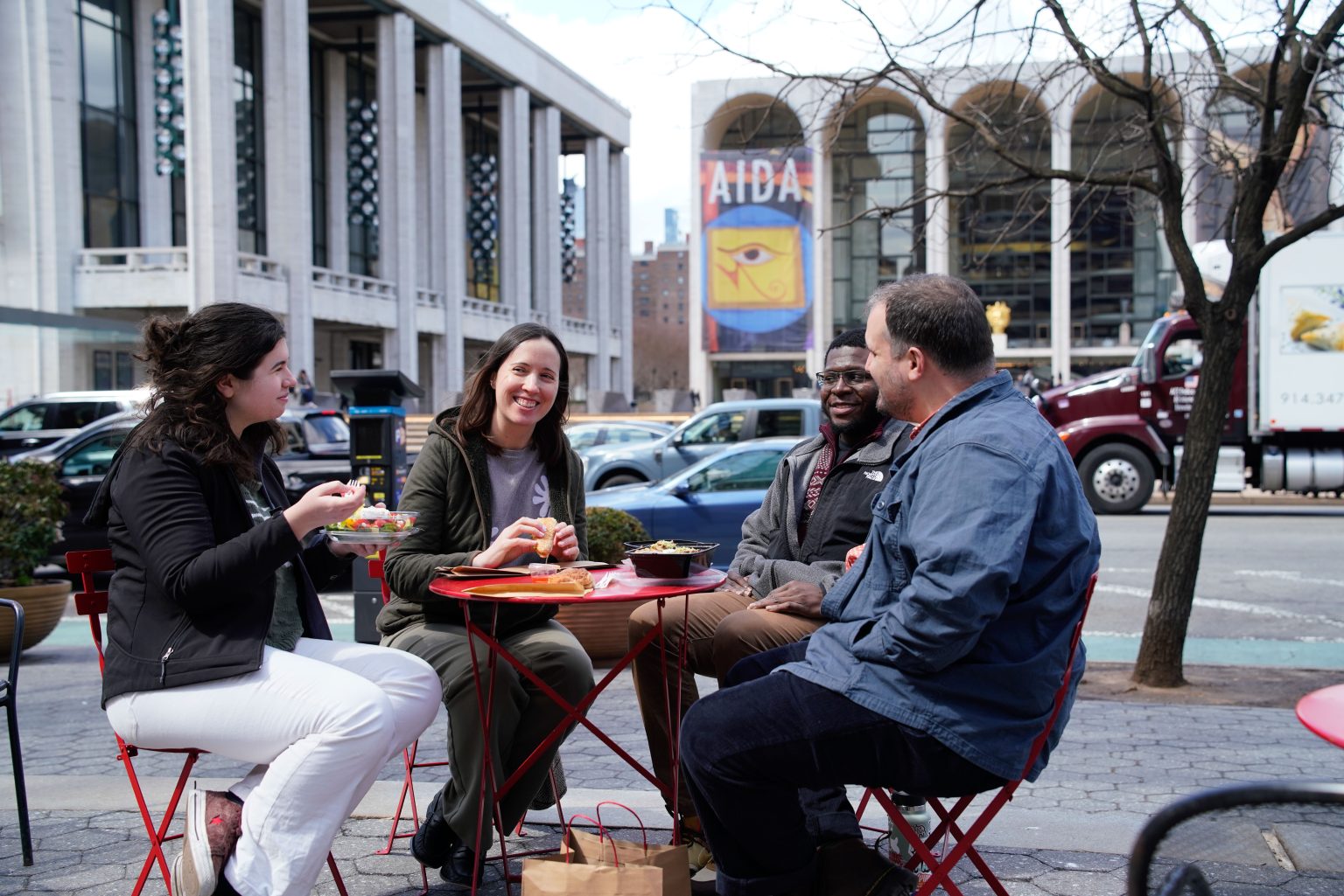 A group of people eating lunch in front of Lincoln Center, representing places to eat and drink near Fordham