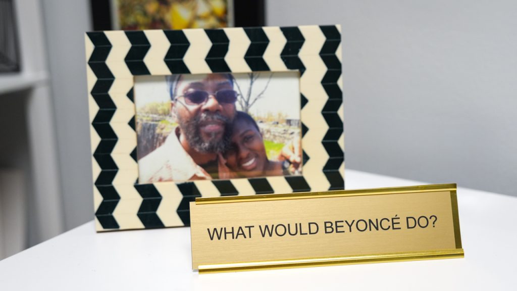 A framed photo of Laurie Lambert with her husband in front of a desk plate that says "WHAT WOULD BEYONCÉ DO?"
