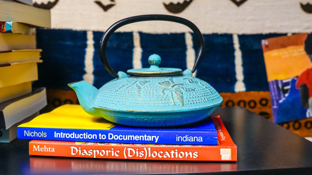 A blue teapot sitting on a stack of books