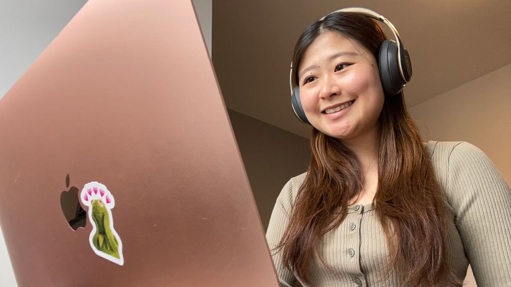 An Asian woman sits in front of a laptop.