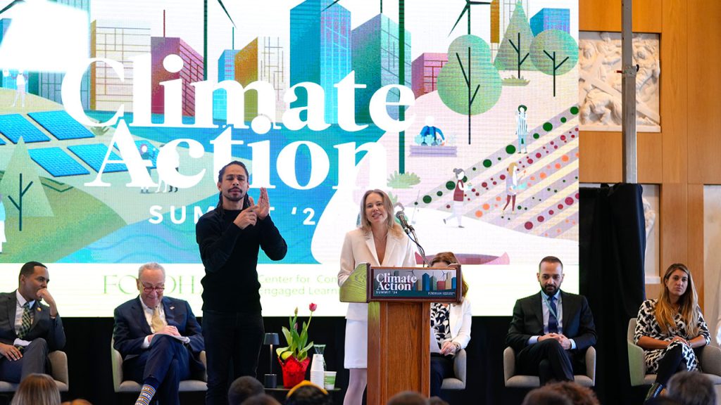 People standing on a stage with a banner behind them that says climate action.