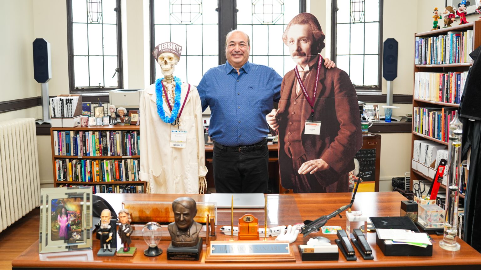 What’s on My Desk: Martin Sanzari Martin Sanzari smiles and stands in front of his office desk, next to a skeleton and a life-sized cardboard cutout of Albert Einstein.