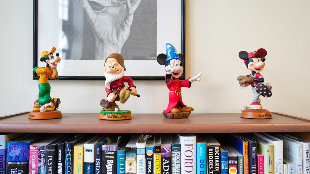 Four Disney character statues on a bookshelf