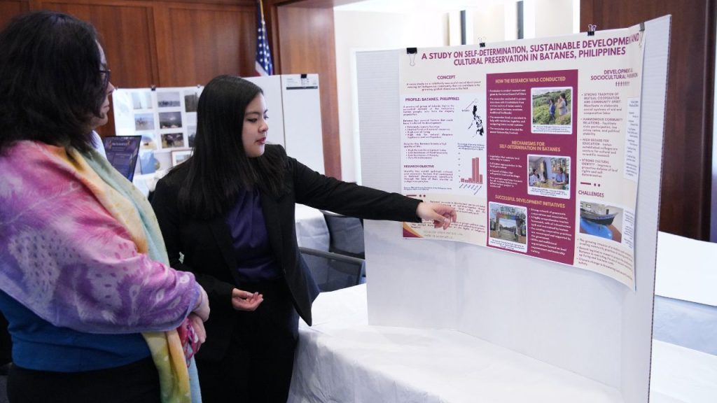 Fordham student Katrina Martinez Luna discusses her project with a woman at the ARS Nova Arts and Research Showcase. 