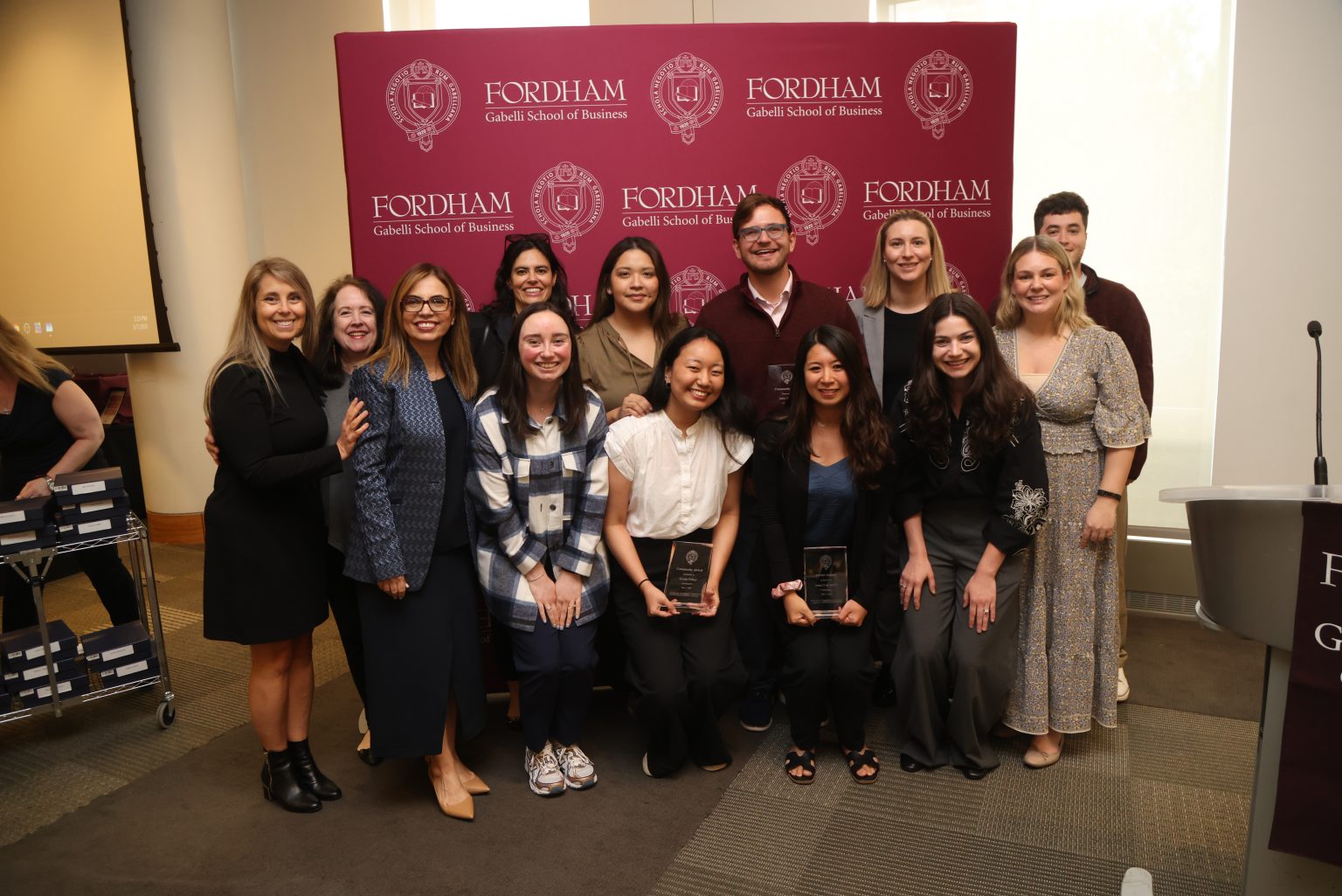 Group photo of award recipients with Dean Aksoy, behind a Fordham school backdrop