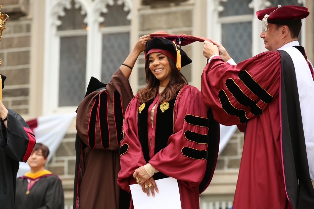 Actress Regina Hall is hooded by two people as part of Fordham's 180th commencement ceremony. 