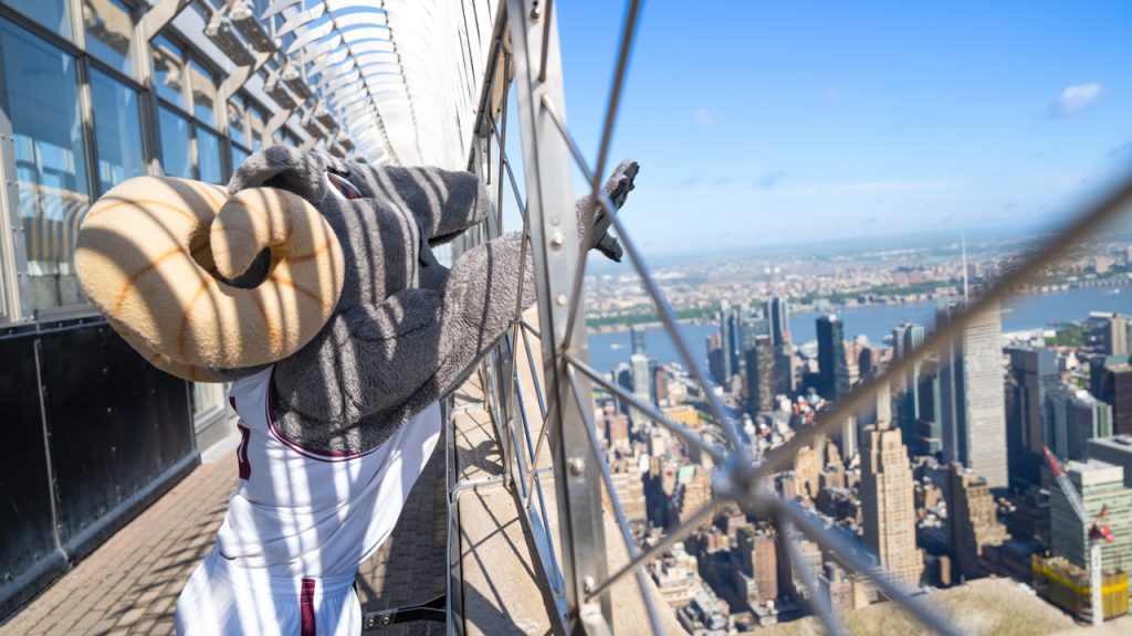 Ramses stretches his hand past the barrier on top of the Empire State Building.