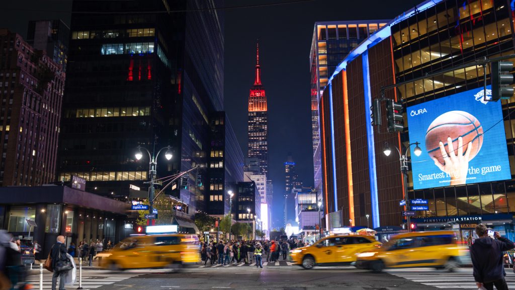 A street-level view of the Empire State Building lit in maroon at night