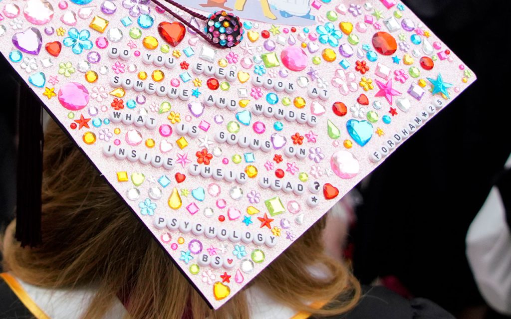 Commencement cap decorated with the message "Do you ever look at someone and wonder what is going on inside their head? Psychology B.S., Fordham '25"