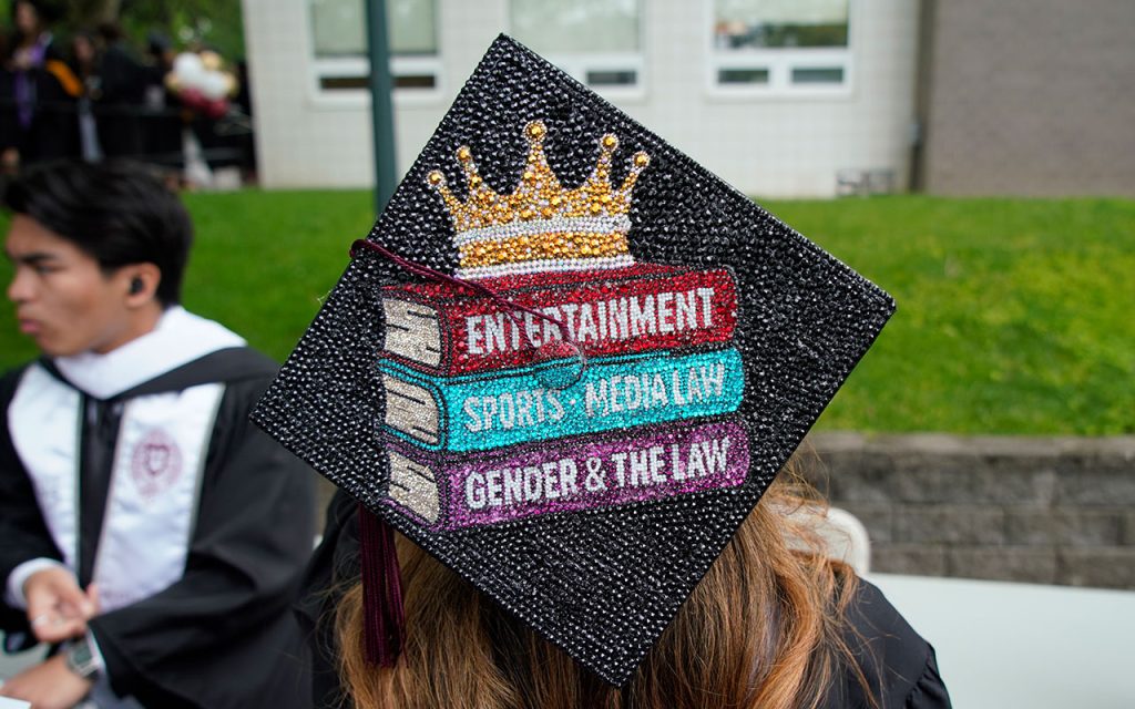 Commencement cap decorated with images of textbooks in entertainment, sports and media law, and gender and the law