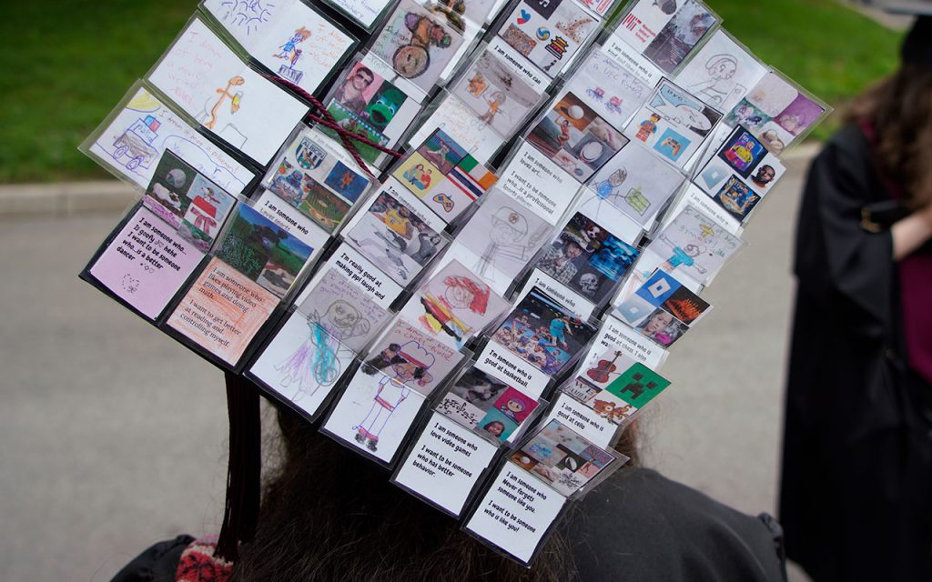 Commencement cap decorated with about two dozen small messages on folded paper