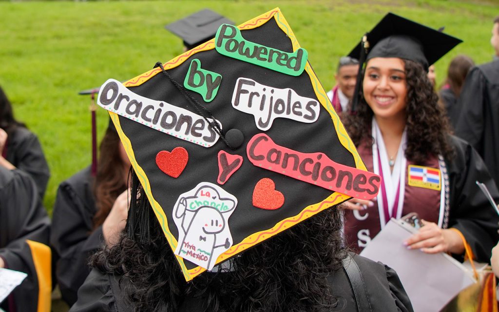 Commencement cap decorated with the message "Powered by friholes, oraciones y canciones"