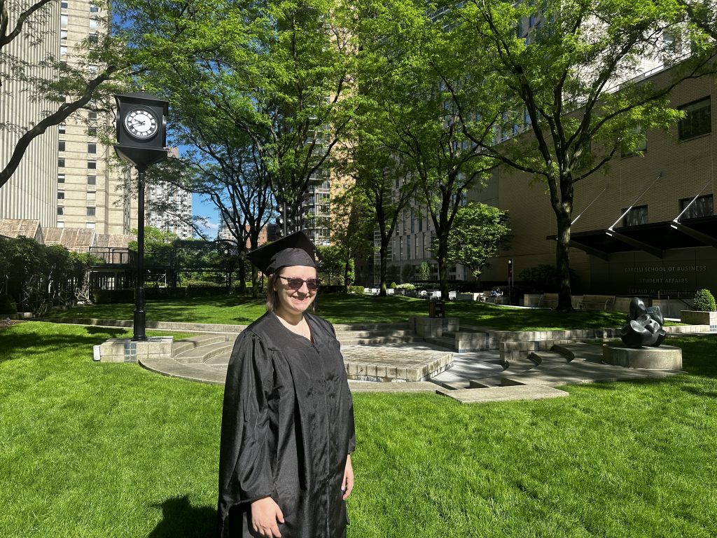 Woman in cap and gown in green the plaza. 