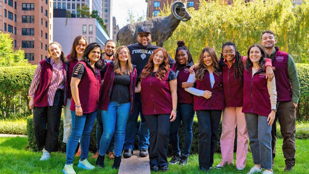 A group of students from Fordham's graduate school of social service stand in front of a statue of a ram, the University's mascot