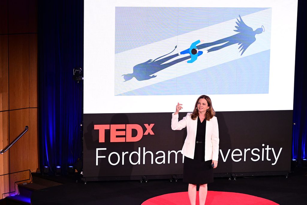 Tania Tetlow speaks from a stage with a Tedx banner behind her.